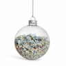 Clear glass Christmas ornament filled with blue and beige decorative stones on a white background