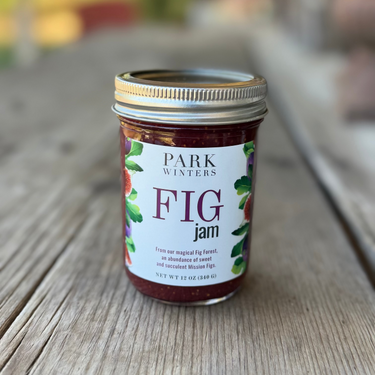 Jar of Park Winters Fig Jam on a wooden surface with a blurred outdoor background