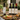 Bottles of Park Street Pantry olive oil and vinegar on a wooden table with a plate of food outdoors.