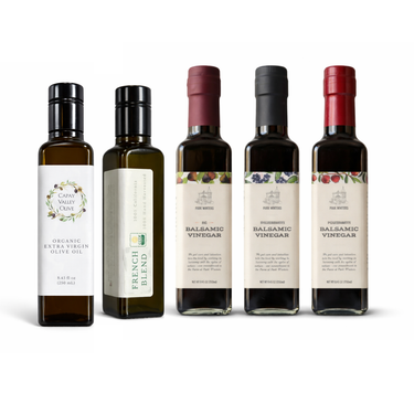 Five bottles of olive oil and balsamic vinegar with labels on a white background