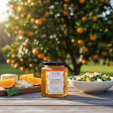 Jar of Park Honey with oranges and salad on a wooden table outdoors