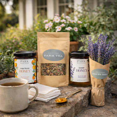 Tea and honey products on a stone surface with flowers in the background